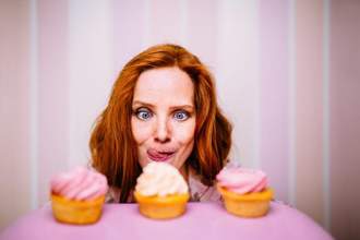woman licking her lips hungrily while staring at cupcakes
