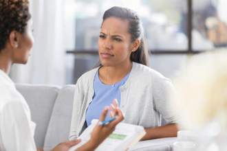 woman looking confused while her doctor explains something