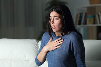 woman looking down holding her hand to her chest as if she has lost her breathe from shock
