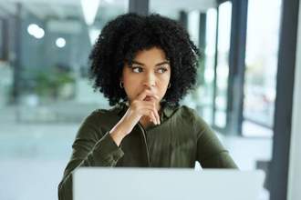 woman looking out the window ruminating at the office desk