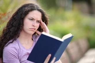 woman reading a book looking confused