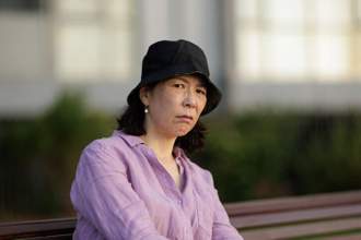 woman sitting outdoors with a confused and slightly concerned expression