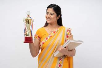 woman smiling holding notebooks and a trophy