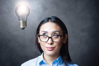 woman staring at the lightbulb above her head while her glasses slide down her nose