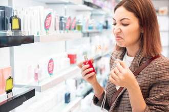 woman with a stink face smelling an overly sweet perfume at the store