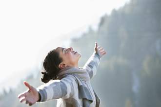 woman with her hands outstretched looking up at the sky