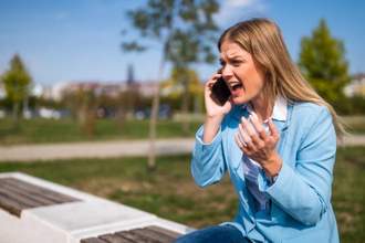 woman yelling on the phone while sitting on a park bench