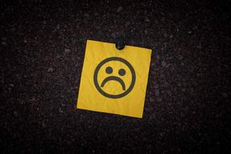 yellow sticky note with a frowning face