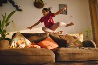 young girl rashly jumping onto a couch