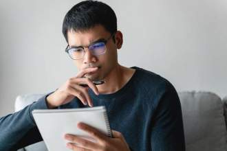 young man looking intently at the notebook in his hand