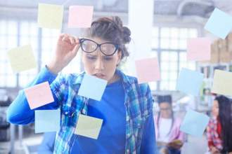 young woman standing behind a glass wall with post-it notes