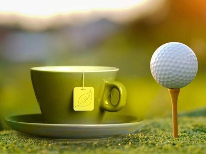 a cup of tea and a golf ball on tee side by side 