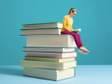 tiny woman sitting on a pile of books reading