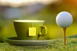 a cup of tea and a golf ball on tee side by side 