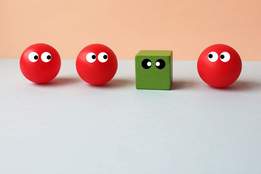 image of a green cube out of place in a lineup of red spheres 
