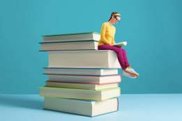 tiny woman sitting on a pile of books reading