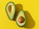 a halved avocado on a yellow background