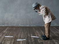 little boy with a magnifying glass looking at footprints